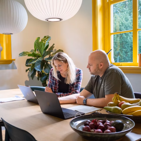 Twee designers van Valsplat in overleg aan een tafel. Ze hebben allebei een laptop voor zich staan.