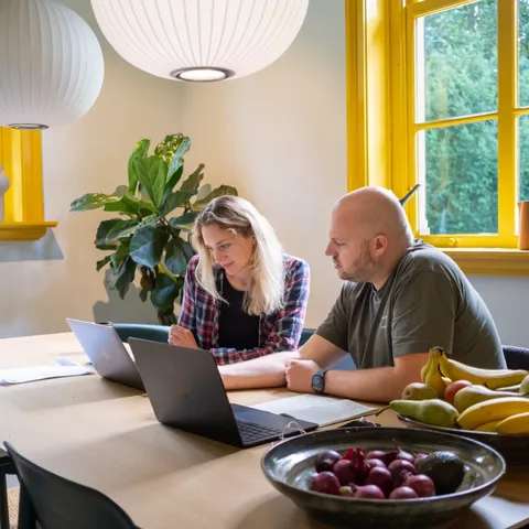 Twee designers van Valsplat in overleg aan een tafel. Ze hebben allebei een laptop voor zich staan.